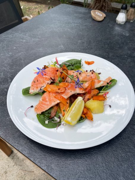 Saumon façon hareng Salmon grillé sur lit d'épinards, accompagné de légumes et de citron.